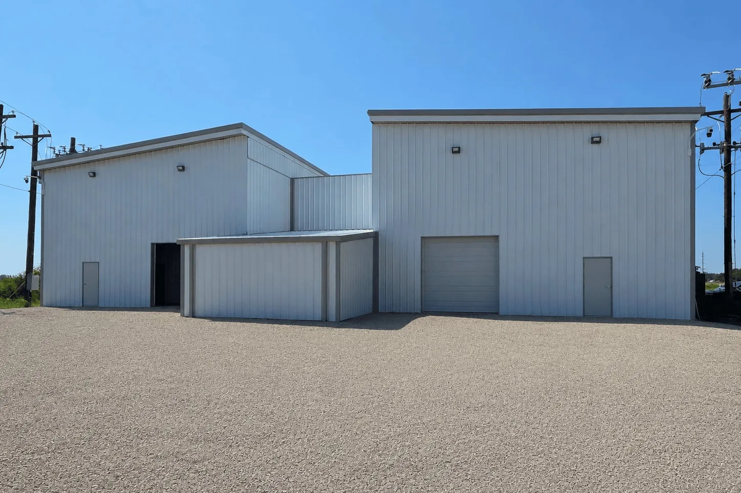 An AAIM facility: two metal-clad buildings on a gravel pad, served by overhead utility lines